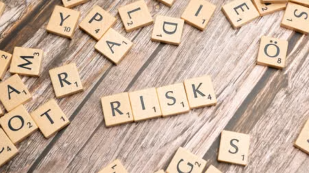 Scrabble tiles spelling out 'risk' scattered on a rustic wooden background