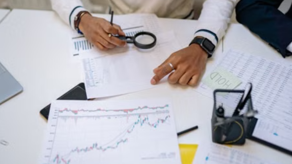 Business professionals reviewing charts with a magnifying glass in an office setting